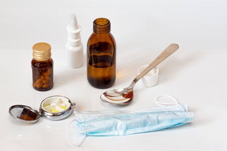 Pandemic of coronavirus COVID-19 Protective surgical mask pills electronic infrared thermometer and two syringe on blue background Concept of medicine quarantineの写真素材