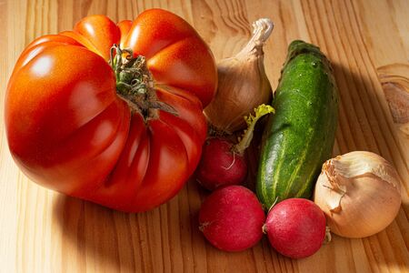 large red tomato cucumber radish and onion on a wooden backgroundの写真素材