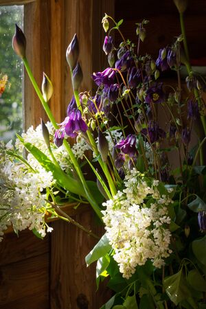 A bouquet of garden flowers against a wooden wall closeupの写真素材