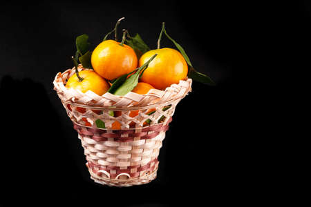 Citrus Ripe orange tangerine with green leaves isolated on a black background organic food full basketの写真素材