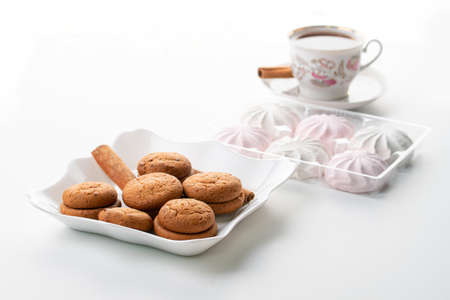 cup of hot tea marshmallow cookies cinnamon selective focus on white background high keyの写真素材