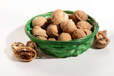 walnuts in a wicker basket and split nuts isolated on a white background with a close upの写真素材