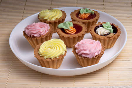 six colourful cupcakes with cream on top in white plate. selective focusの写真素材