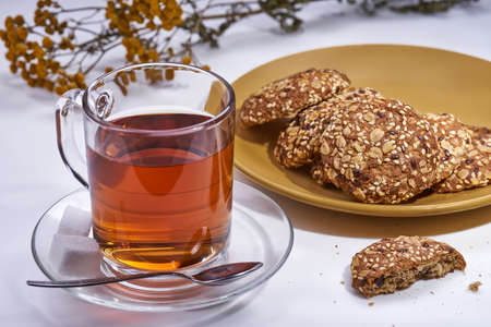 A cup of tea a plate with cookies yellow flowers on a white backgroundの写真素材