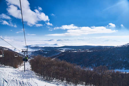 chairlift on the slope of the ski slope against the background of snowy mountains on a sunny dayの写真素材