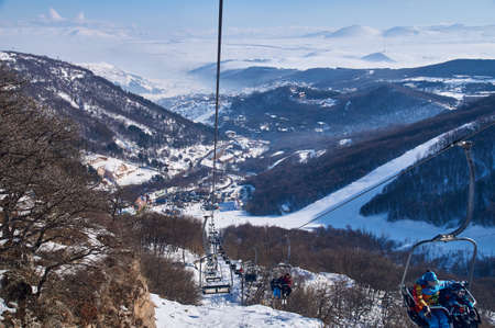chairlift on the slope of the ski slope against the background of snowy mountains on a sunny dayの写真素材