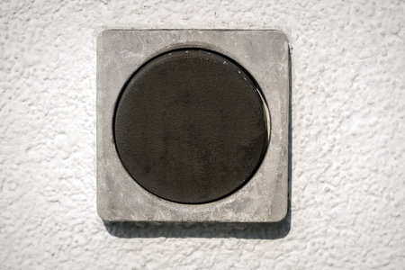 Close-up of a dark square switch on a white wall