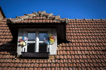 and small window decorated with windbreaks in the red roof of a small village houseの写真素材