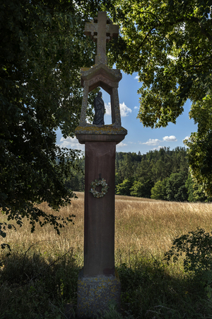 stone statue of divine torture among the trees on a field path in the summerの写真素材