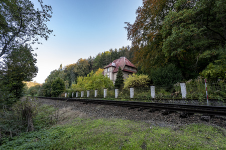 and a large villa with a red roof standing in the woods near the train tracksの写真素材