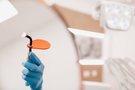 Dental instrument in hand with blue gloves on a white background. Dental clinic hygieneの写真素材