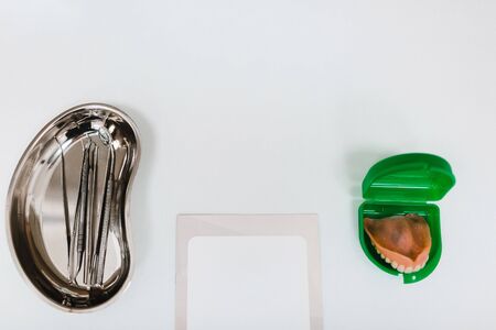Dental instruments, denture and and a clean notepad on a white table at the clinicの写真素材