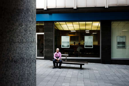 Barcelona, Spain. May 2020. An elderly man sits alone on a bench. A beautiful European street without people.のeditorial素材