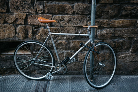 Old retro bike fastened to a pipe against the background of an old stone wall