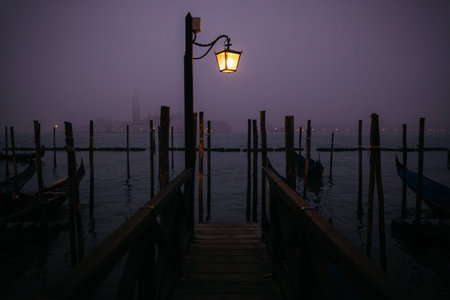 A burning street lamp on the waterfront in the evening in Venice, Italy.