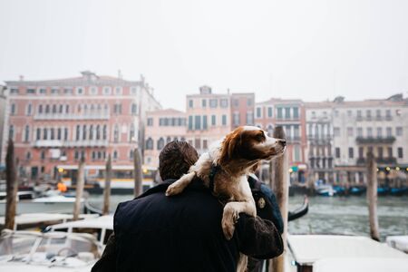 The dog is carried in his arms in Europe. Venice, Italy.の写真素材