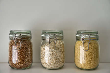 Glass jars with lid food, white shelf. Storage of cereals, pasta on kitchen.の写真素材