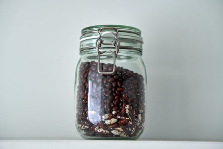 Glass jars with lid for food on a white shelf. Storage in kitchen. Beansの写真素材