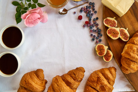 Croissants and Americano coffee for French Breakfast with rose. Berries ontable.