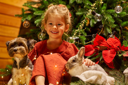 Merry Christmas girl with dog and rabbit. Laughing child in red dress.の写真素材