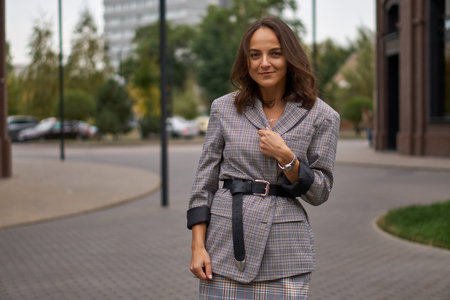 A woman in a gray dress walking on street. Office style. Fashionable brunette.の写真素材