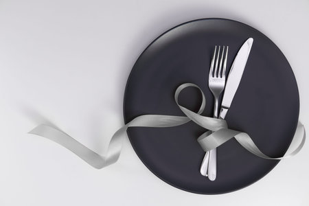 Table setting with gray plate and ribbon. Fork and knife for a holiday dinner on a holiday date....