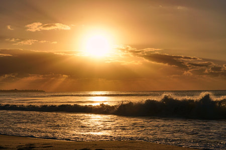 Sun rises over horizon dawn sea. Ocean at sunset. Sandy beach wave on seashore.