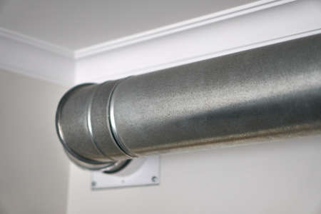 Grey stainless steel pipe in the kitchen near the white ceiling. Range hood.の写真素材