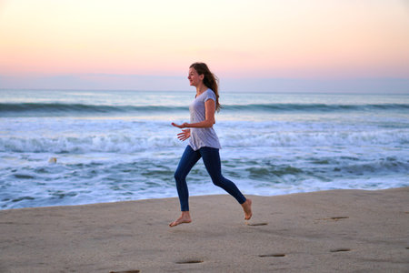 Play catch-up on the shore. Caucasian woman in jeans and a tank top plays on the sand. Beach fun on...