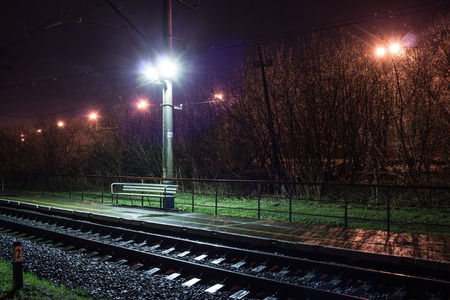 Railway station at spring night with a passing trainの写真素材