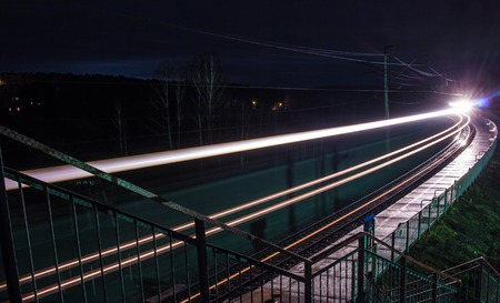 Railway station at spring night with a passing trainの写真素材