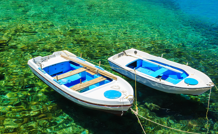two boats at the dock in clear water, which can be seen the bottom and stonesの写真素材