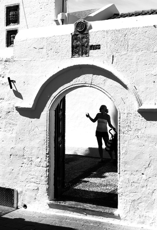 Silhouette Girl photographing tourists in arch at door of old church city of Lindos .の写真素材