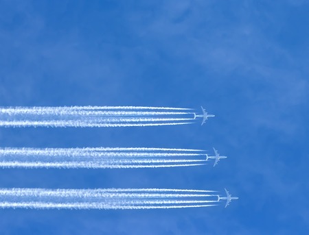 three airplanes leaving horizontal traces on a clear blue sky.の写真素材