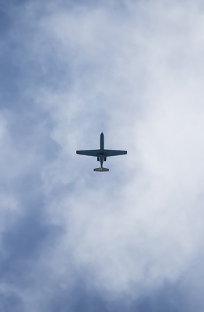 A plane flying in the blue sky with white cloudsの写真素材