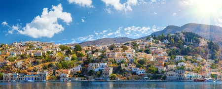 Panoramic shot of the Harbour at Symi Greece with a traditional fishing boat in the foreground. Greece Europe.の写真素材