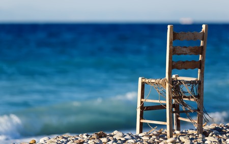 Lonely wooden chair on pebble beachの写真素材