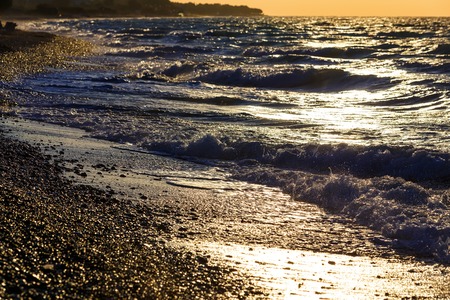 sunset on the beach with black sand. Aegean sea, pebble beachの写真素材