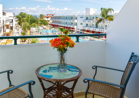 Balcony with chairs and table overlooking swimming pool at luxury tropical hotelの写真素材