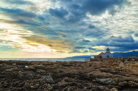 White little Church on the shore of the sea of Crete. Early morning , the break in the rain clouds in the skyの写真素材