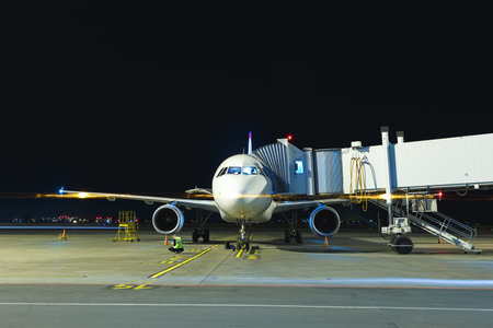 Modern white passenger airplane standing on parking place at night and get ready for boarding...