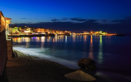 Beautiful evening with night shore with a beach and umbrellas and highlighted with bright colorsin Hersonissos bay Crete, Greeceの写真素材