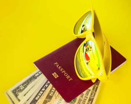 yellow glasses with reflection of aircraft on top of passport, which invested dollars on a yellow backgroundの写真素材