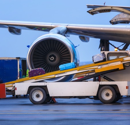 three suitcases are loaded on the transport ladder to the plane in airportの写真素材