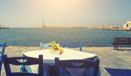 view from the taverns on waterfront of Chania lighthouse, sea, bench, bright Sunny day, the rays of the sunの写真素材
