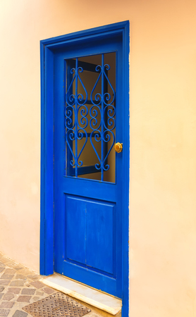 Iconic blue wooden door against clear white wall and colorful flowers. Typical view for Greek islands, Greeceの写真素材