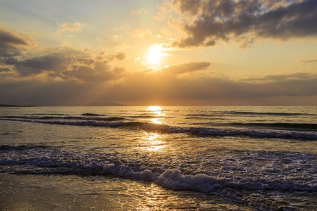 Romantic evening and magic sunset on sandy beach of Crete, Greece. Walk on the beach during beautiful sunset. Silhouette beautiful mountains on horizon and clean sky.の写真素材
