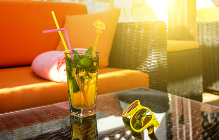 exotic cocktail and Stylish yellow sunglasses in rays of sun . Fresh summer cold alcohol drinks. Greece, Europeの写真素材