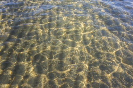 The background of sand on the seabed through layer of clear and transparent sea waterの写真素材