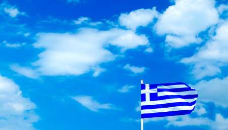 Greek flag fluttering in the wind on a background of blue sky with clouds
